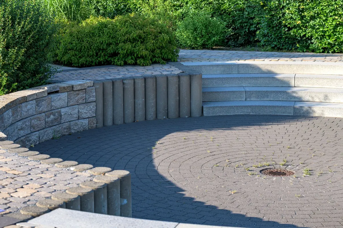 Modern curved block retaining wall with wide steps and charcoal pavers